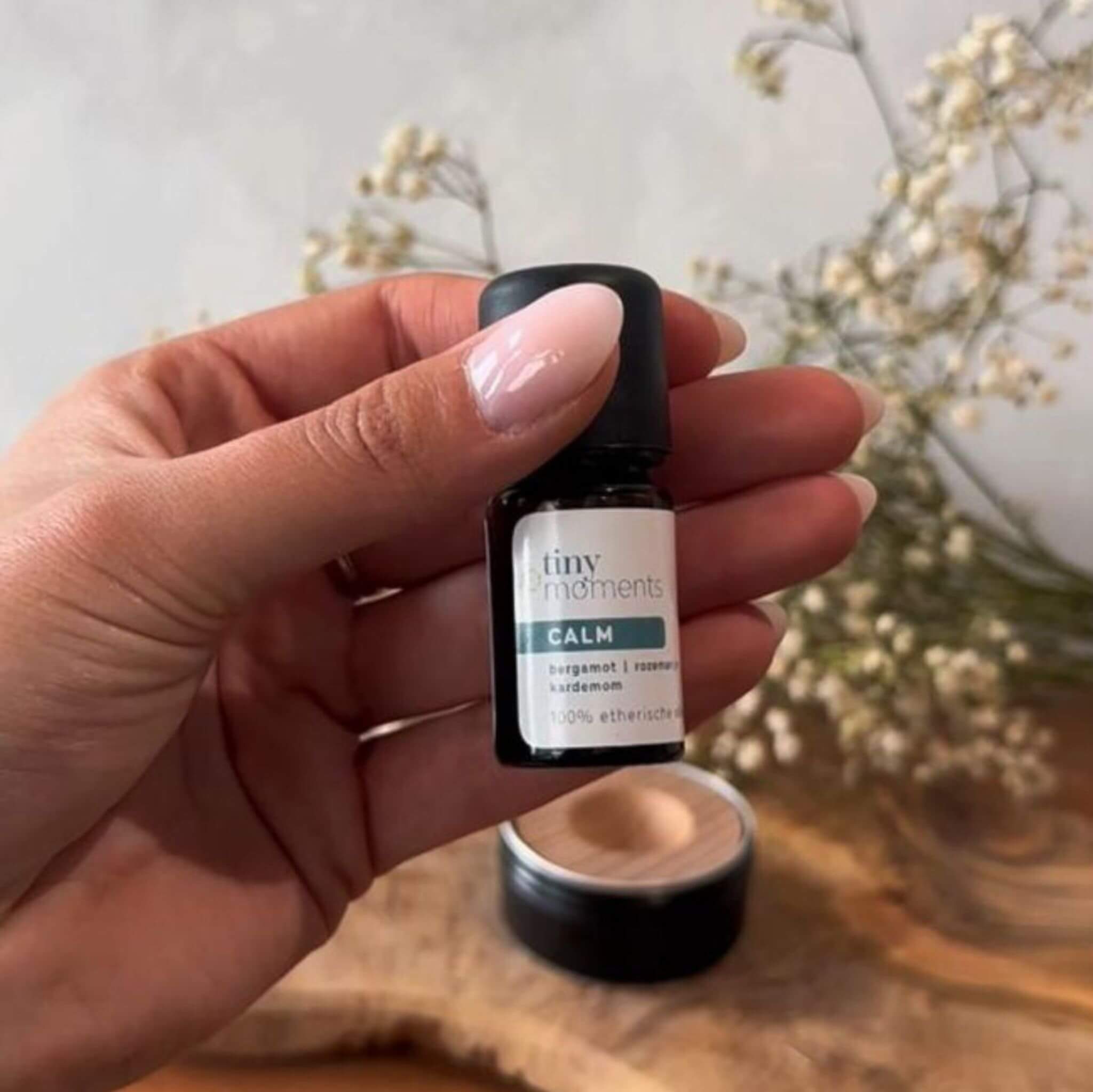Tiny Moments Etherische Olie Calm in hand met pocket diffuser op achtergrond